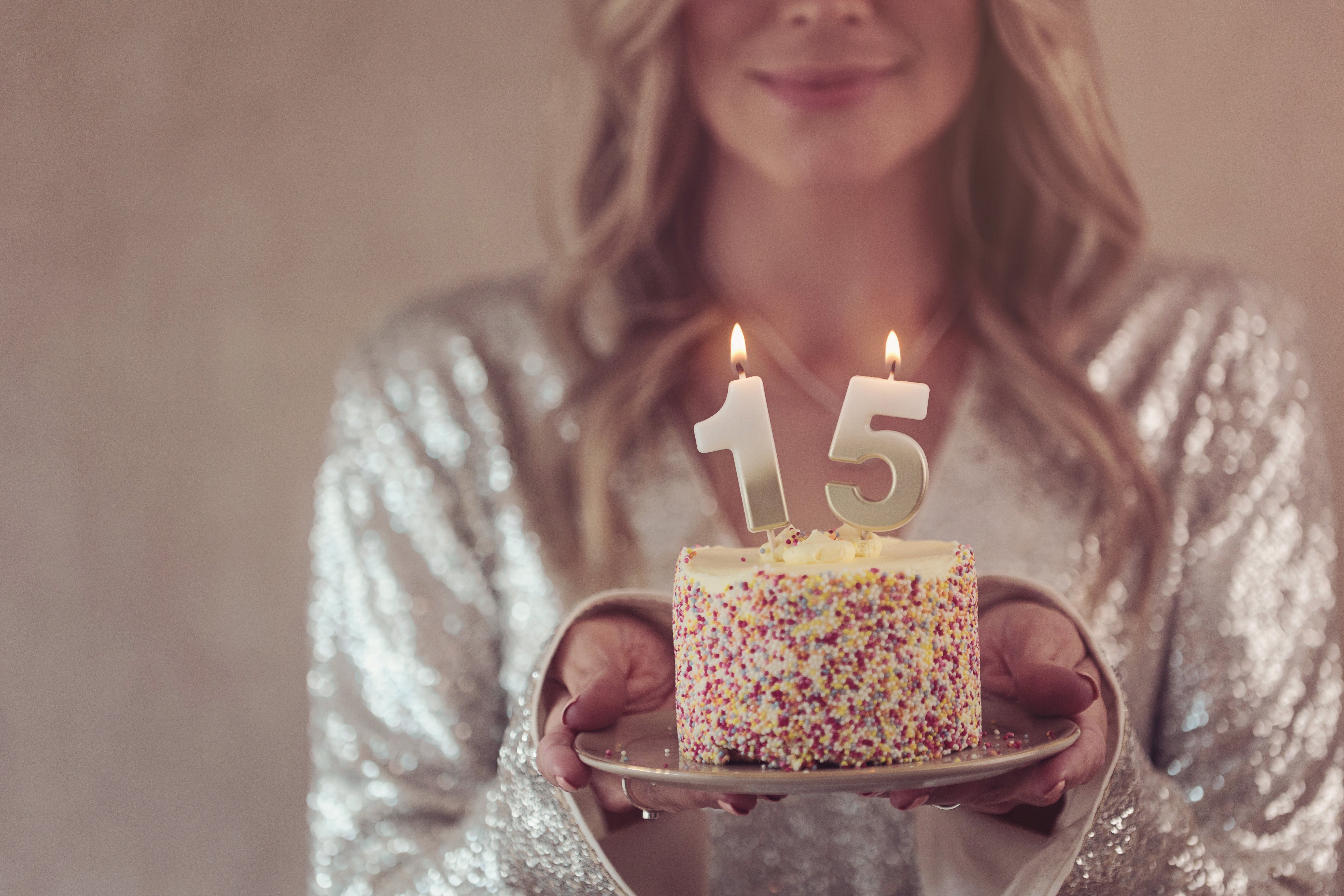 A woman holding a birthday cake with 15 candles