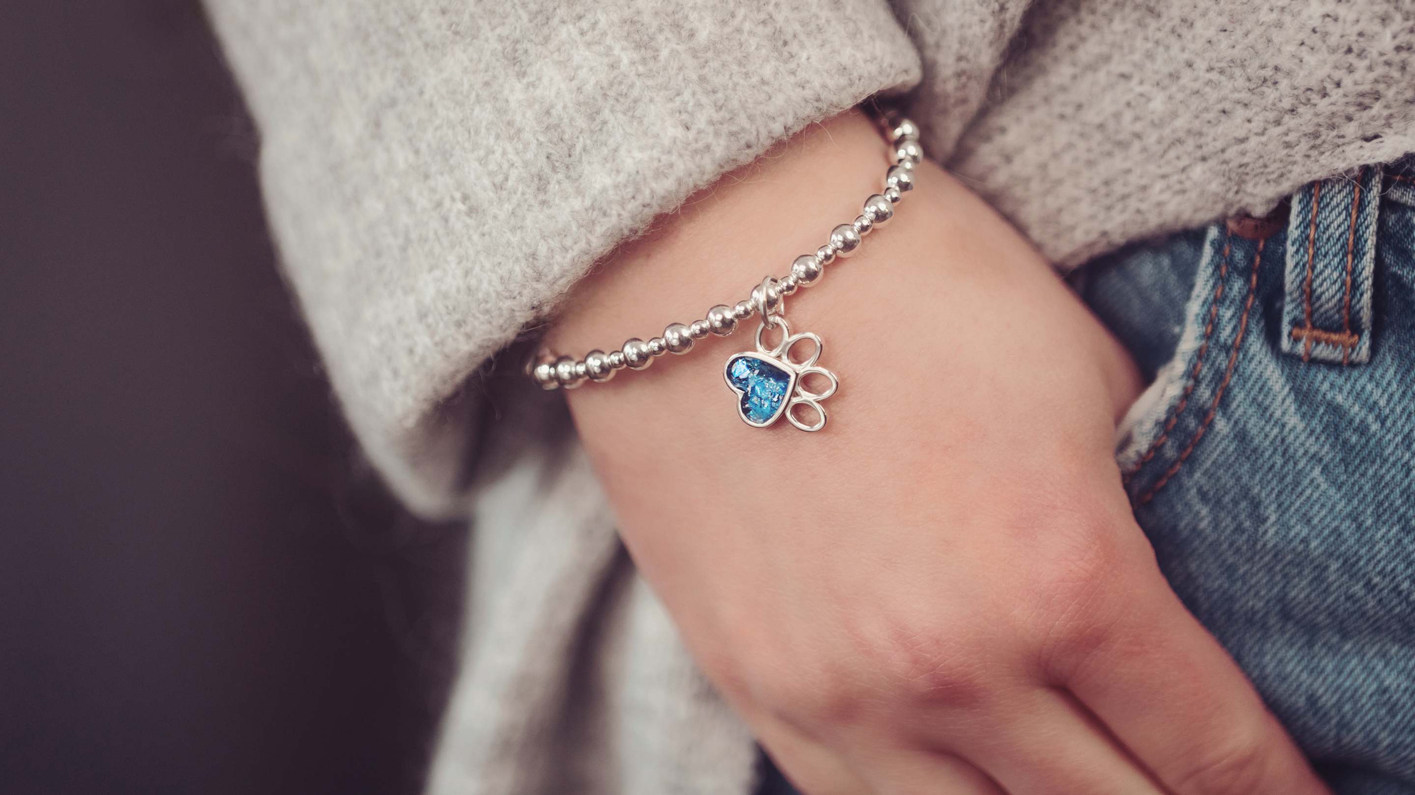 A person wearing a Pawprint Cremation Ashes Bracelet in blue