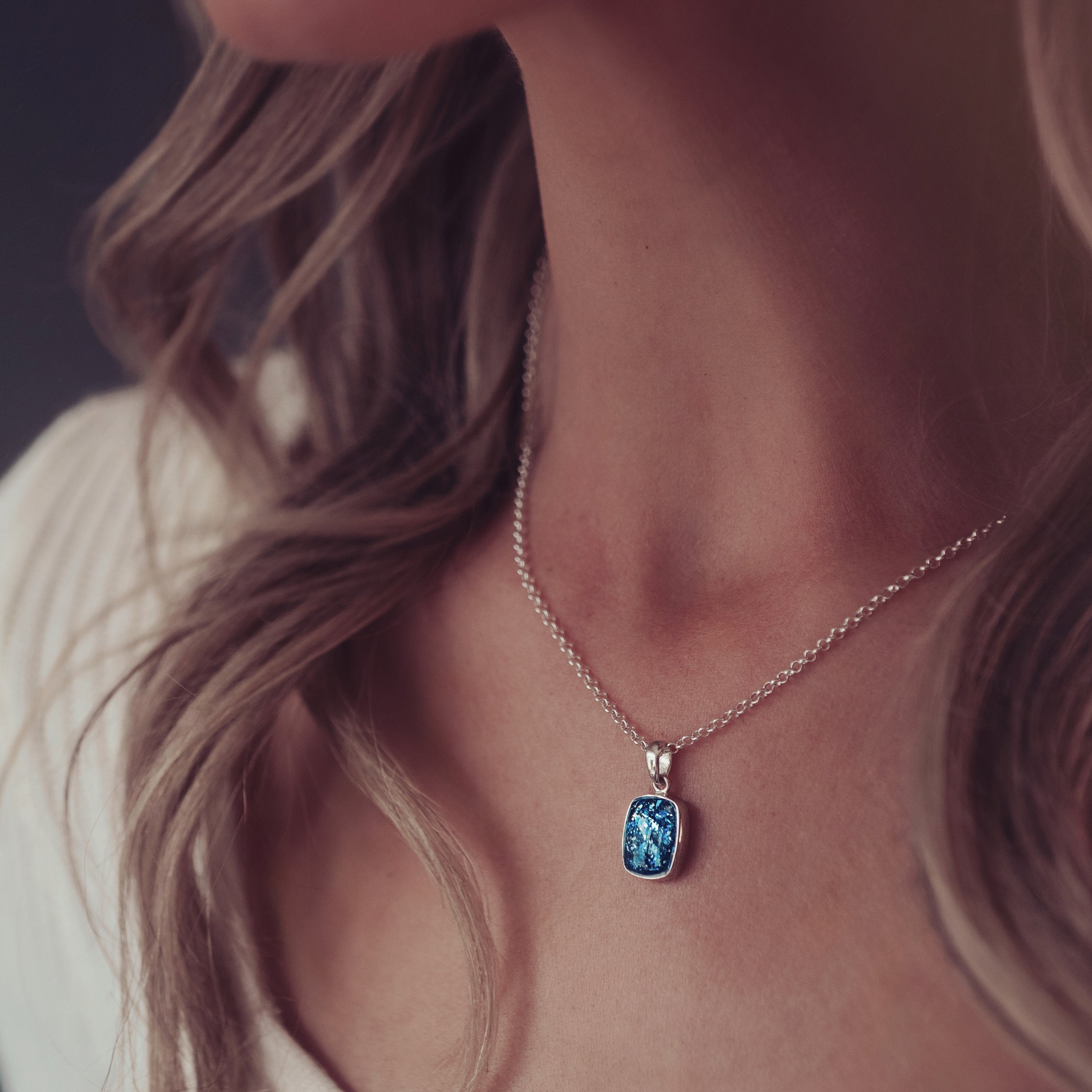 A woman wearing a blue tag necklace containing cremation ashes