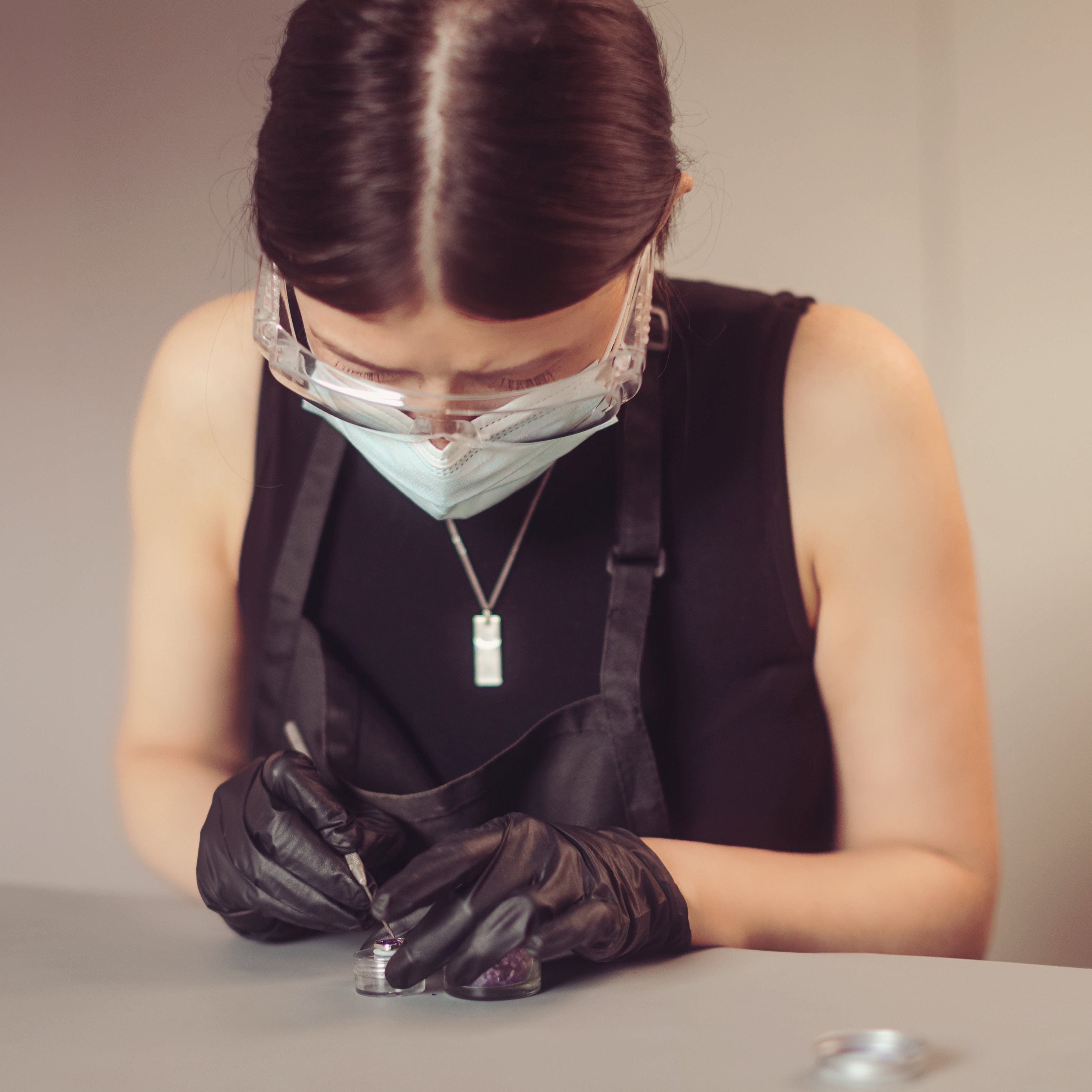 Woman wearing a protective glasses, mask and gloves crafting a piece of ashes jewellery