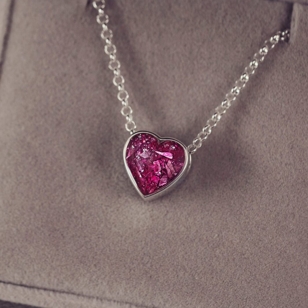 pink heart pendant, filled with crystals, glitter and memorial ashes, on a silver chain.