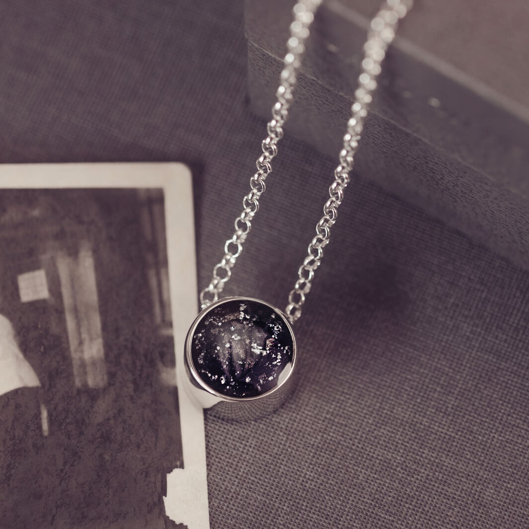 Round silver charm on silver chain, filled with black crystal, glitter, resin & ashes. 