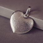 The dimpled reverse of a Sterling silver Large Heart necklace, displayed on a grey background.