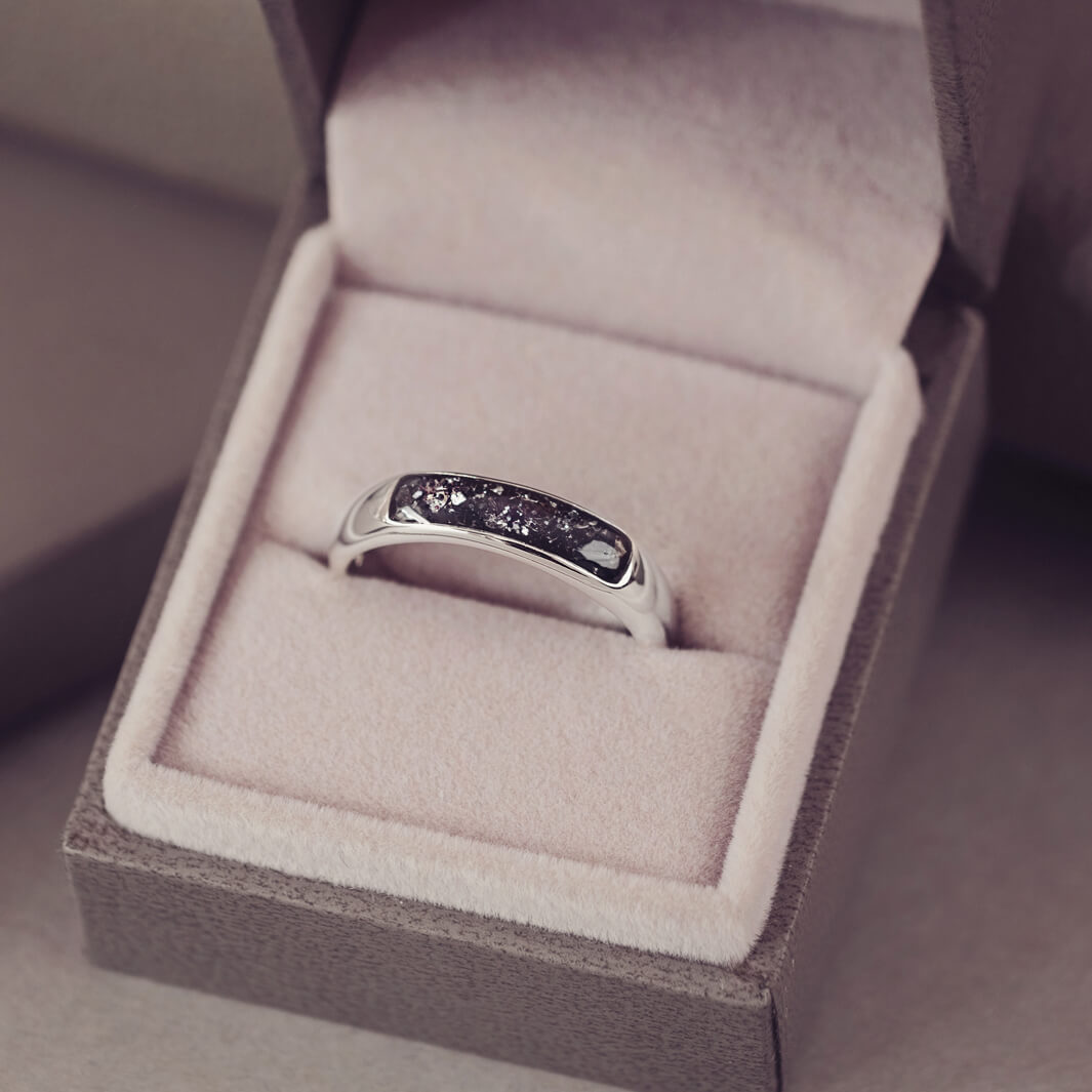 Sterling silver Mens Band Ring with a central section filled with memorial ashes and black crushed crystals, displayed in a grey jewellery box