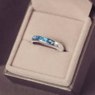 Sterling silver womens ring band with a central section filled with  memorial ashes and blue crushed crystals, displayed in a grey jewellery box