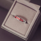 Sterling silver womens ring band with a central section filled with  memorial ashes and red crushed crystals, displayed in a grey jewellery box