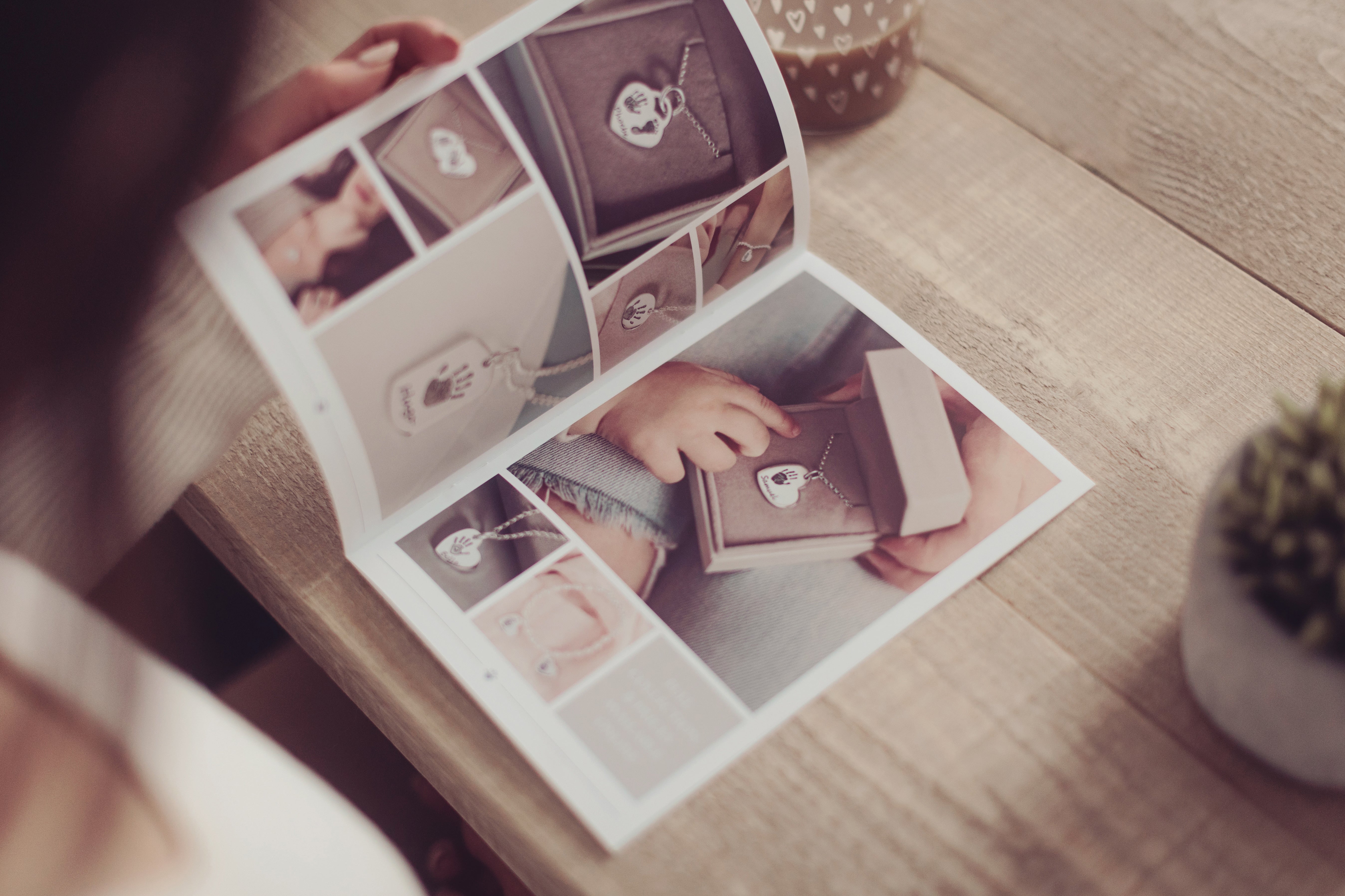 A woman browsing our brochure featuring multiple images of handprint jewellery