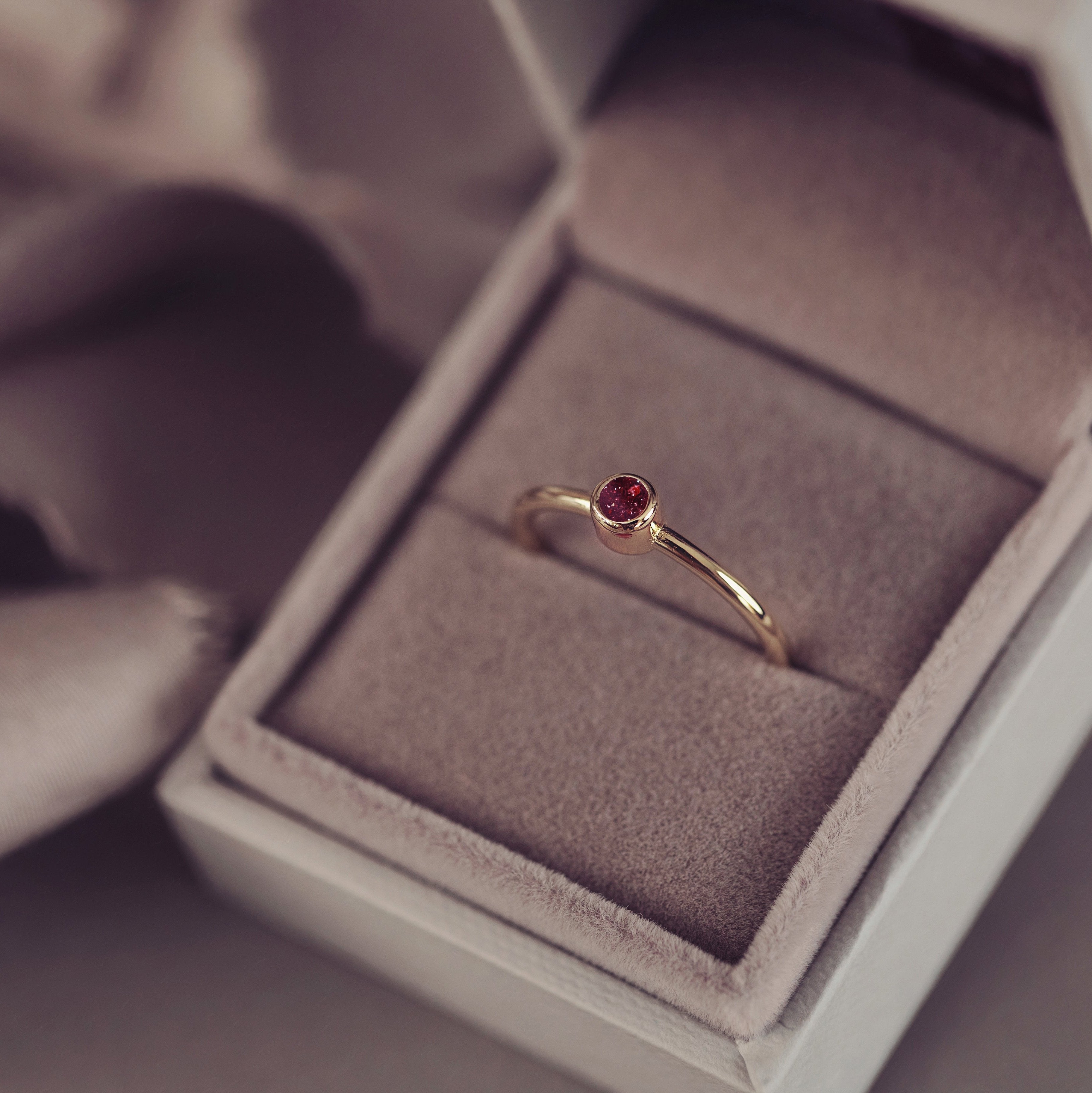 Elegant gold ring in red made from cremation ashes, displayed in a soft velvet lined jewellery box