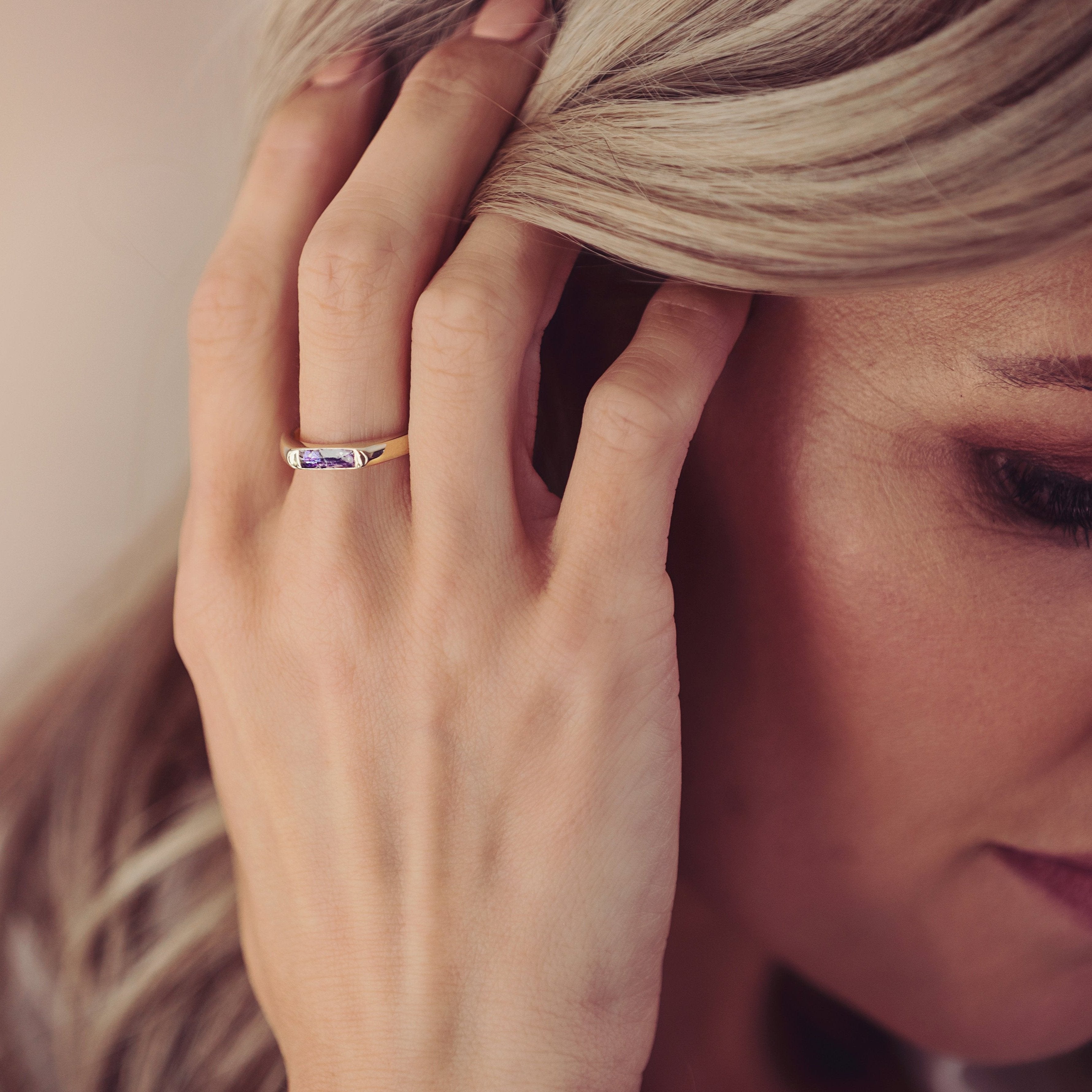 Woman wearing gold ashes ring with purple crystals in band