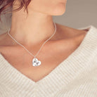 A Silver heart necklace with two handprints on the front