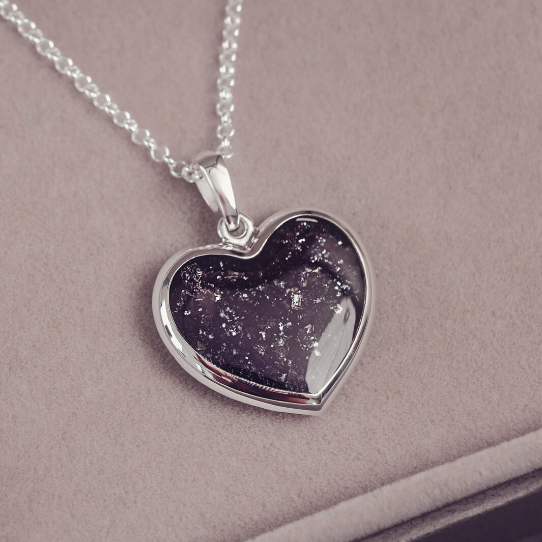 A sterling silver large heart pendant, hanging on a sterling silver belcher chain. The centre of the heart is filled with black crystal and ashes.