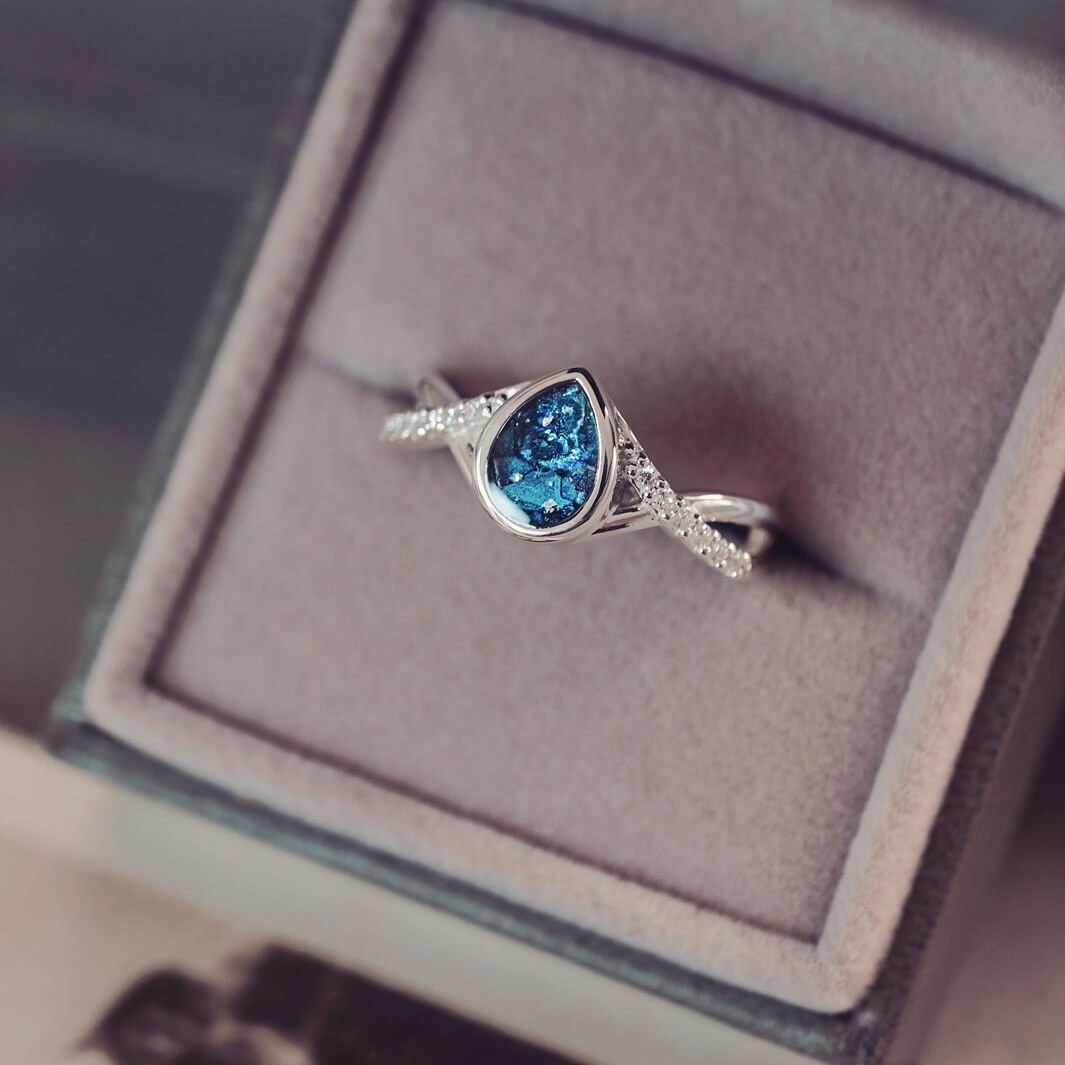 Sterling silver, peardrop shaped ring with a blue stone, created using cremation ashes and crystal