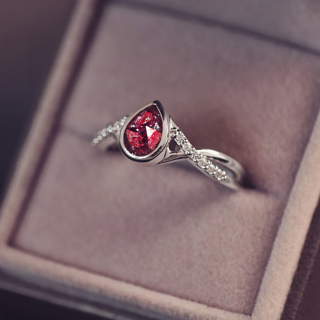 Sterling silver, peardrop shaped ring with a red stone, created using cremation ashes and crystal