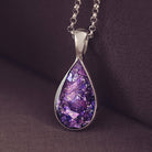 Teardrop shaped sterling silver pendant, filled with purple crystals and cremation ashes