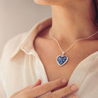 Close up of a lady wearing a Sterling silver Large Heart necklace with a central section filled with memorial ashes and blue crushed crystals.