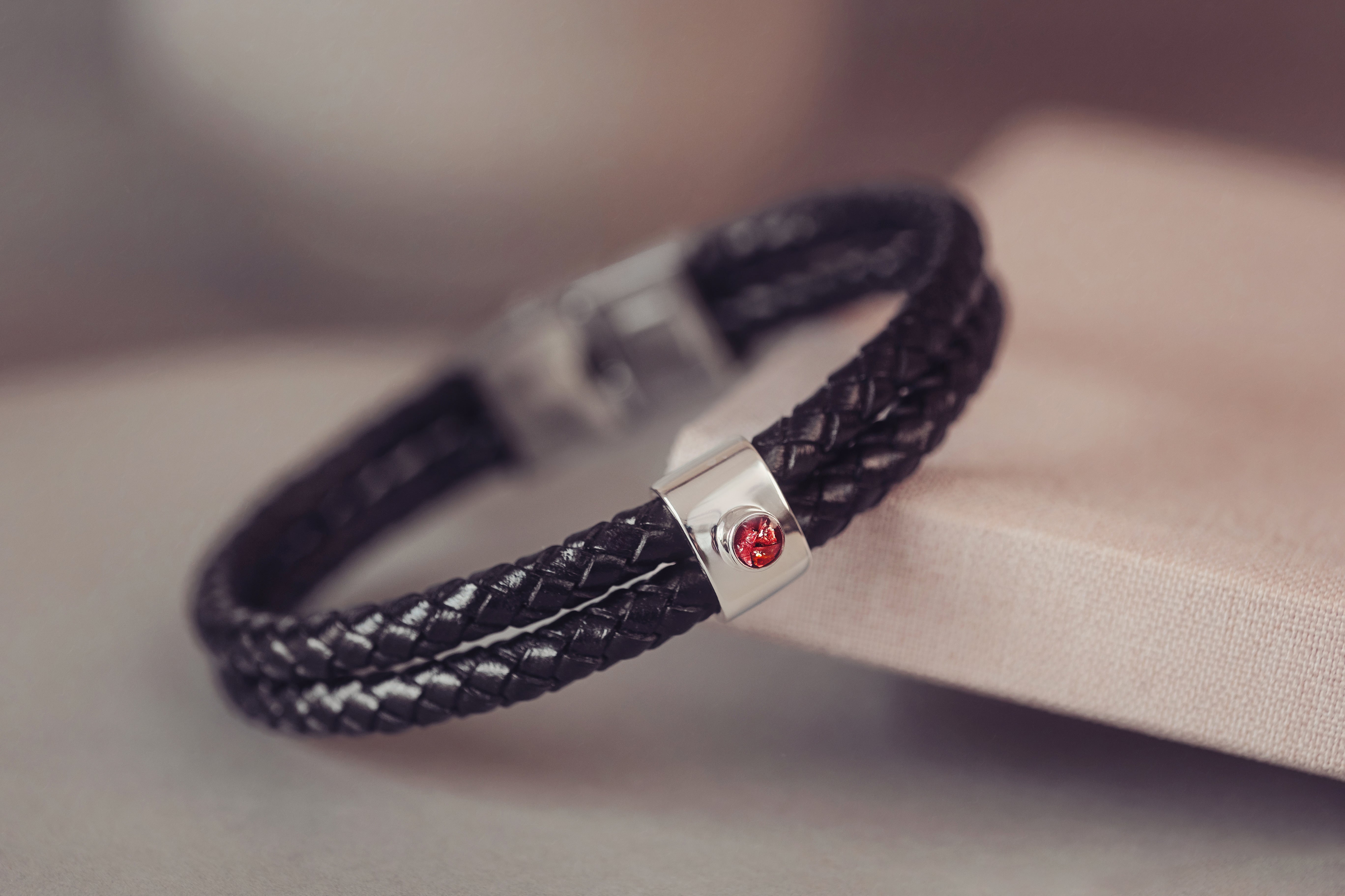 A black leather bracelet featuring a red circle containing cremation ashes