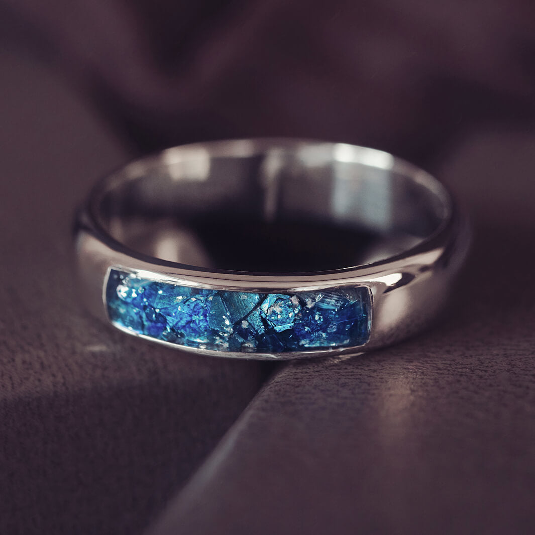 Sterling silver Mens Band Ring with a central section filled with memorial ashes and blue crushed crystals, displayed on a grey background