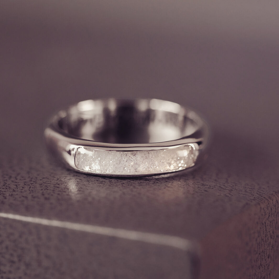 Sterling silver Mens Band Ring with a central section filled with memorial ashes and clear crushed crystals, displayed on a grey jewellery box