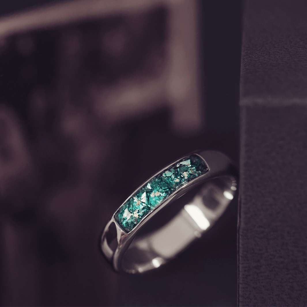 Sterling silver Mens Band Ring with a central section filled with memorial ashes and green crushed crystals, displayed on a dark grey background