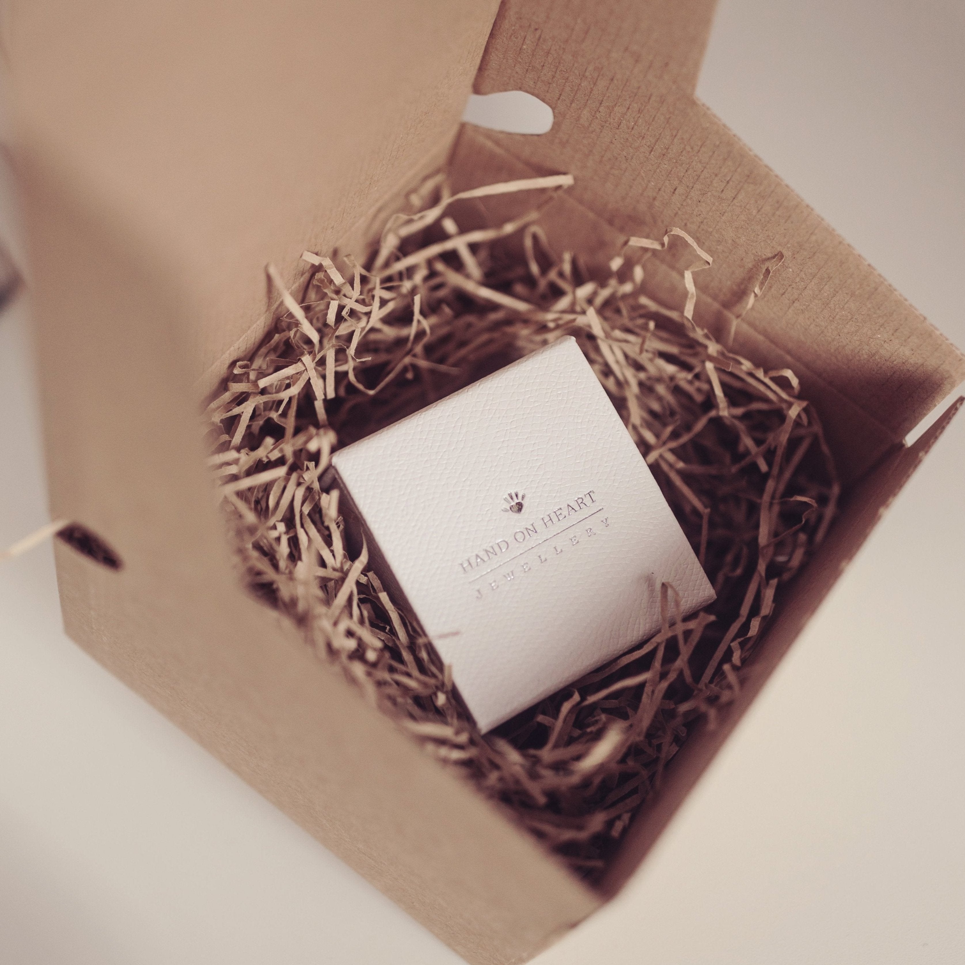 Close up of a Hand on Heart jewellery box nestled in eco-friendly, shredded packing material inside a cardboard gift box