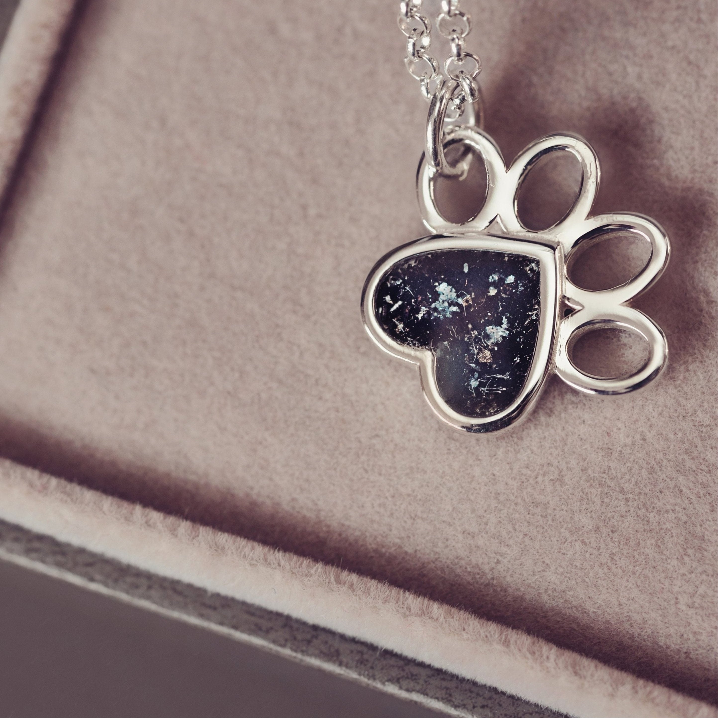 A dog paw necklace with black crystals containing cremation ashes