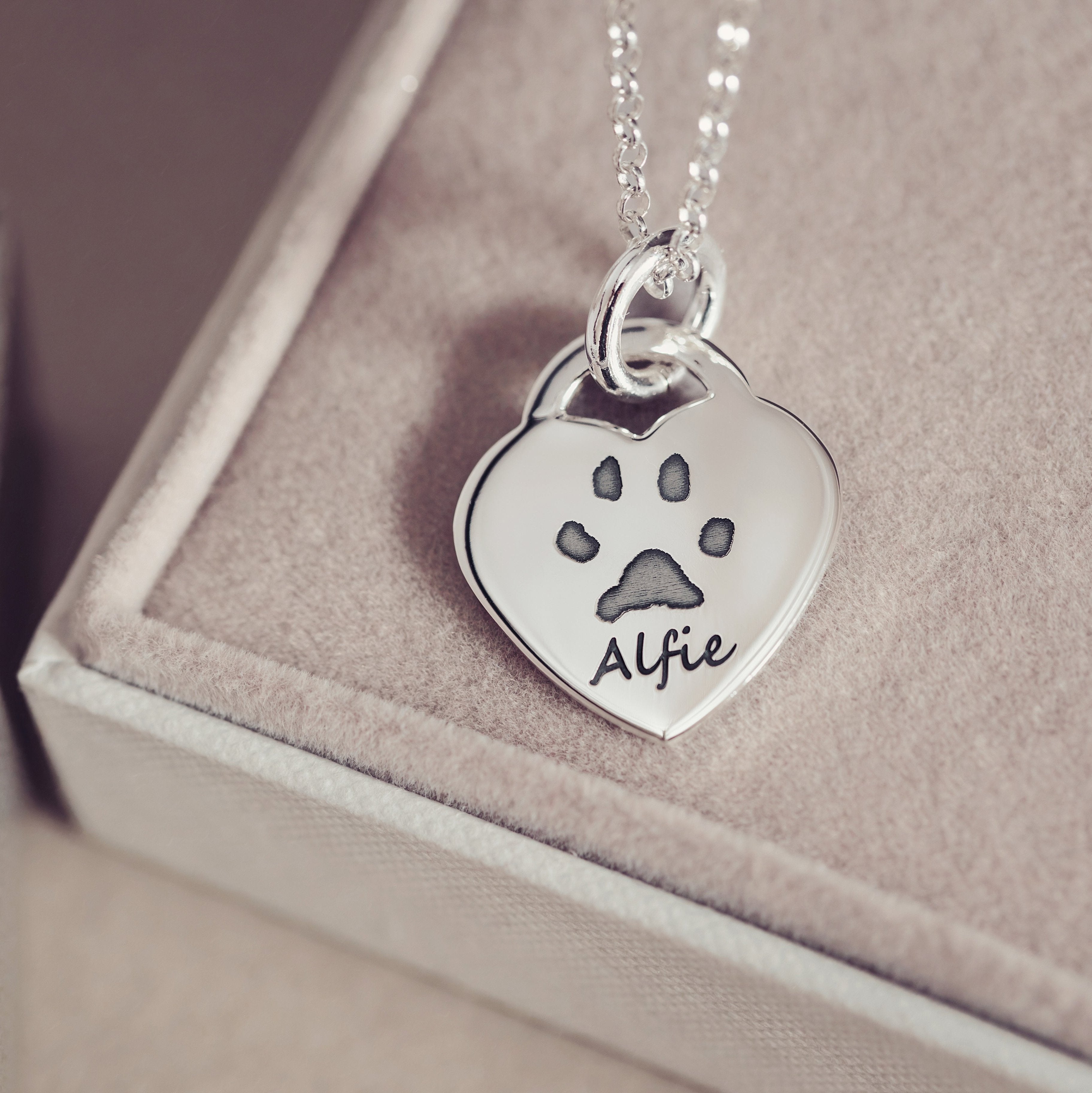 A delicate heart necklace featuring a pawprint and name 'Alfie' engraved