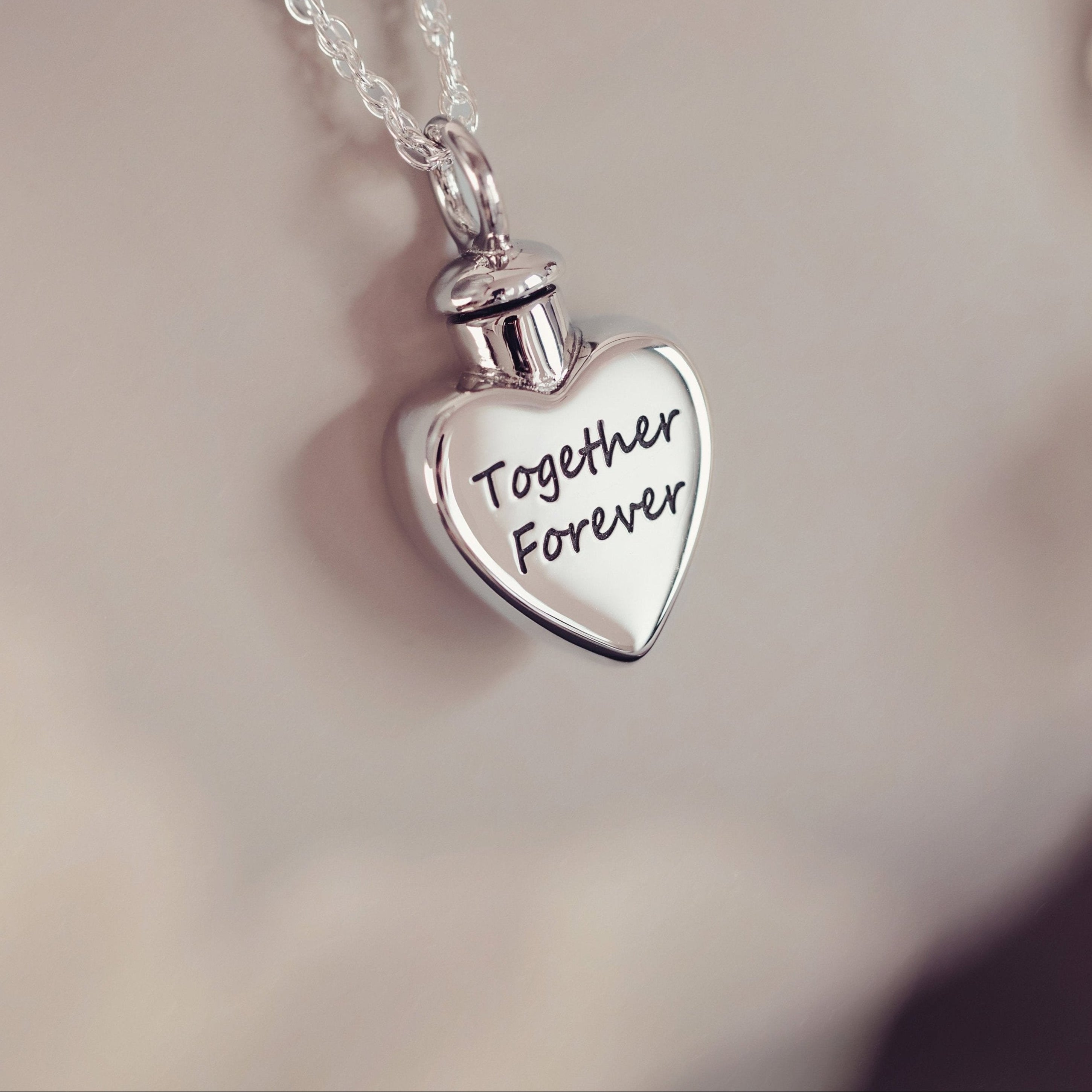 A heart shaped silver locket engraved with the words 'together forever'