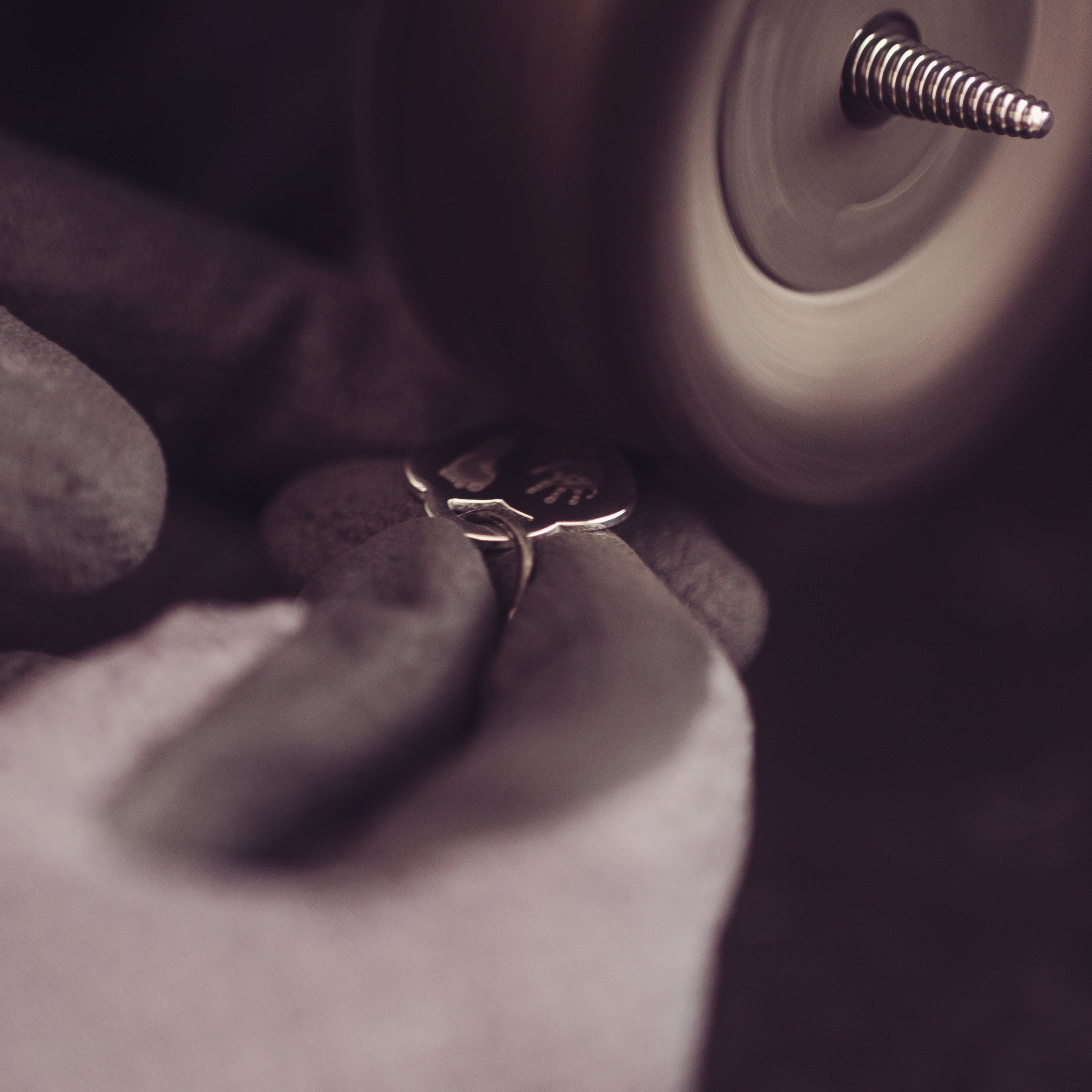 A close up of a heart handprint pendant being polished on a polishing wheel