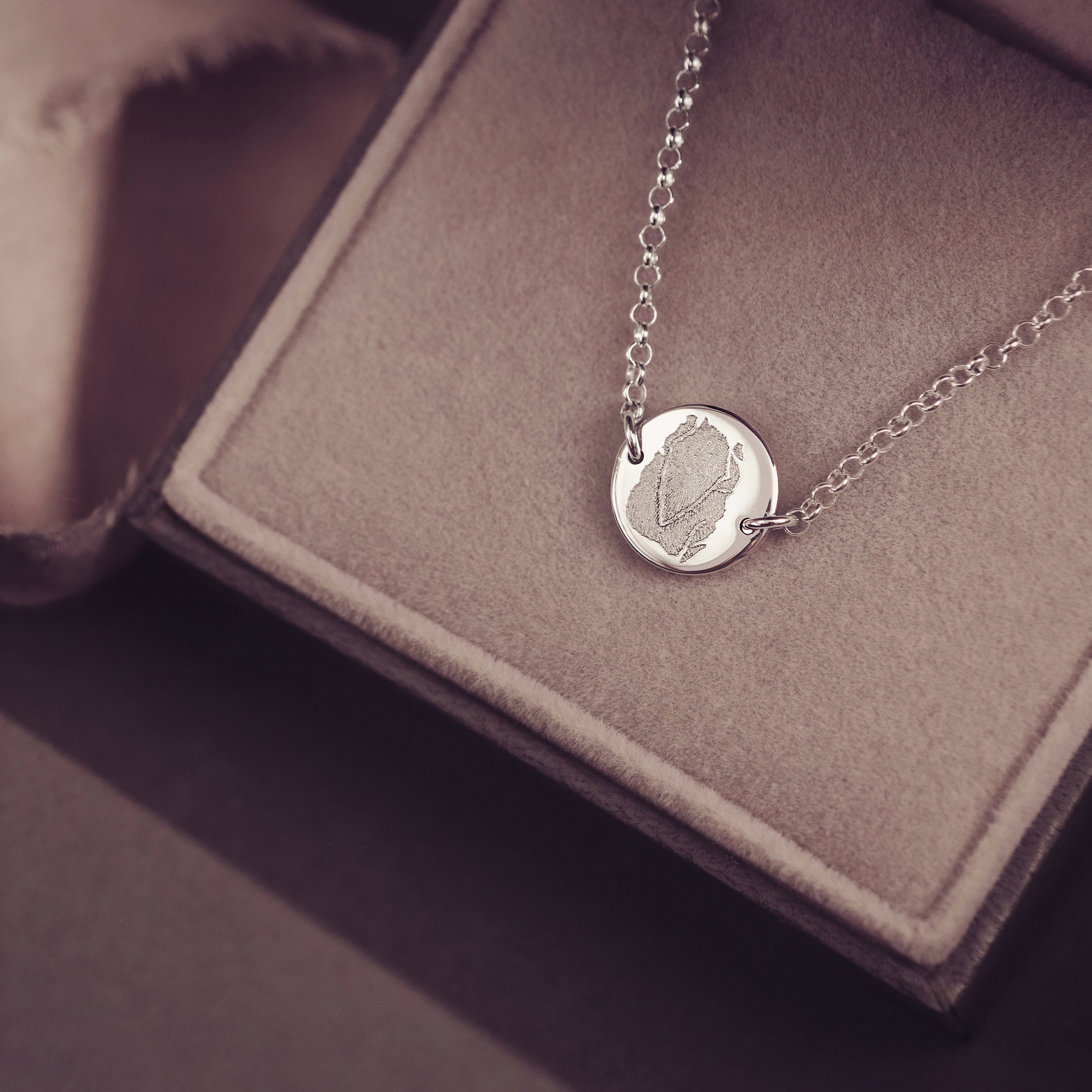 Sterling silver round fingerprint bracelet displayed in a grey velvet jewellery box 