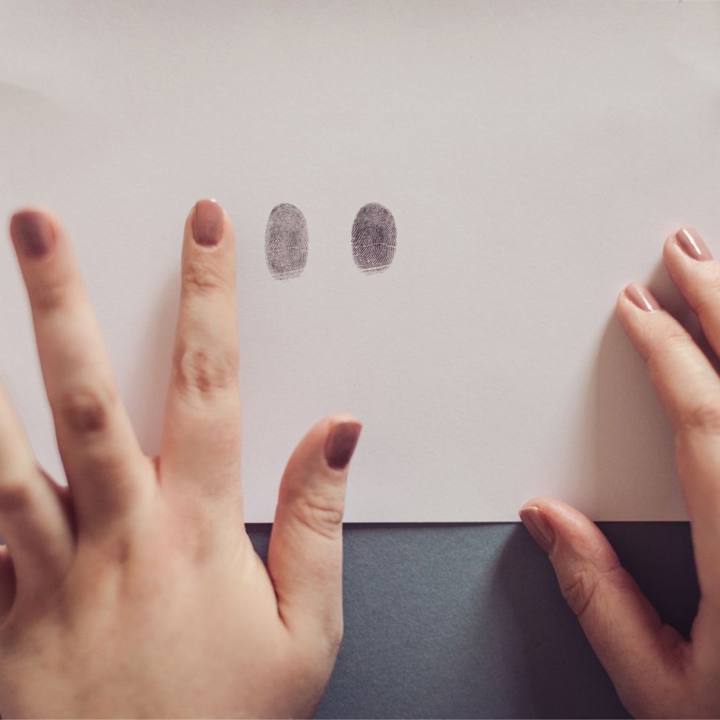 A person demonstrating the fingerprint kit on a piece of paper featuring two distinct fingerprints