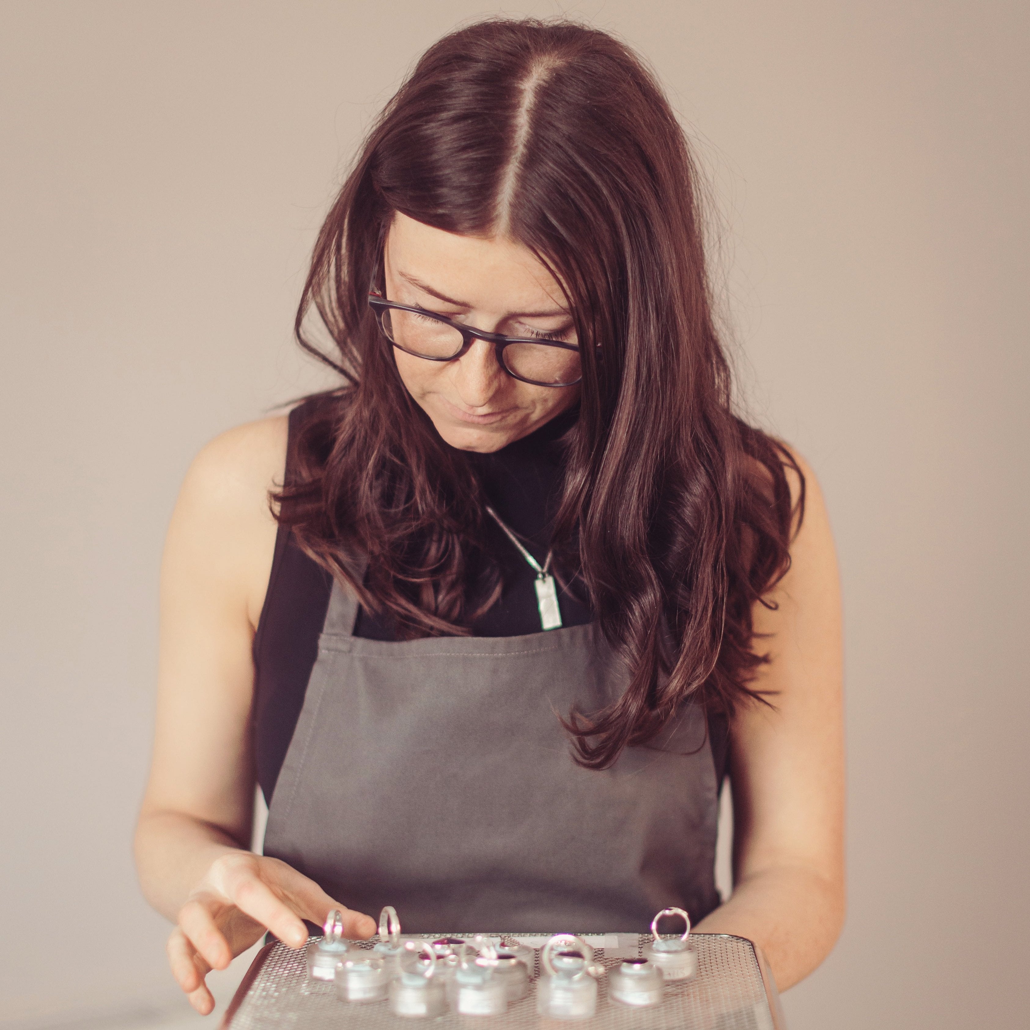 A woman in an apron holding a tray of cremation ashes rings