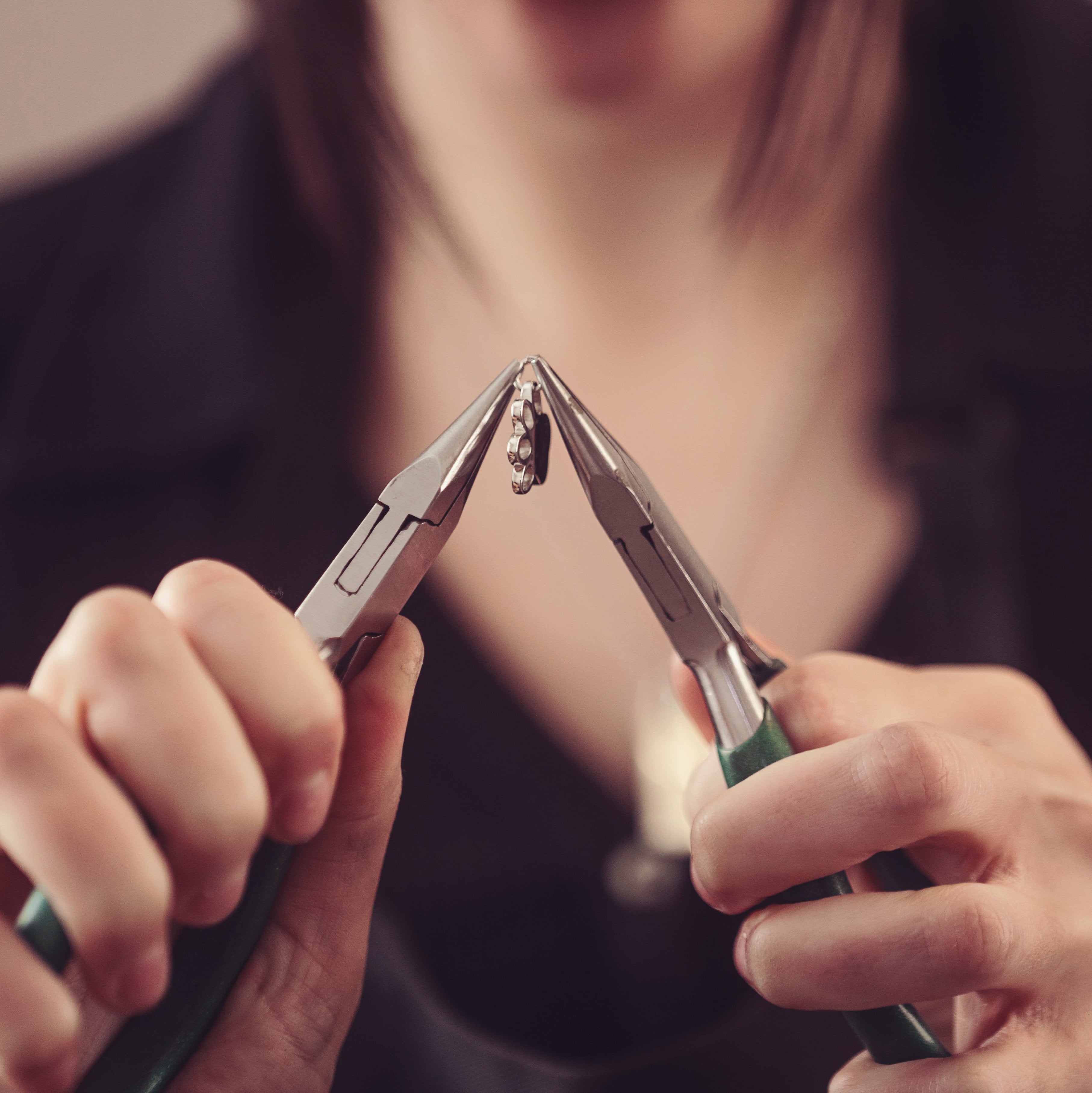 A team member holding a pendant with pliers 