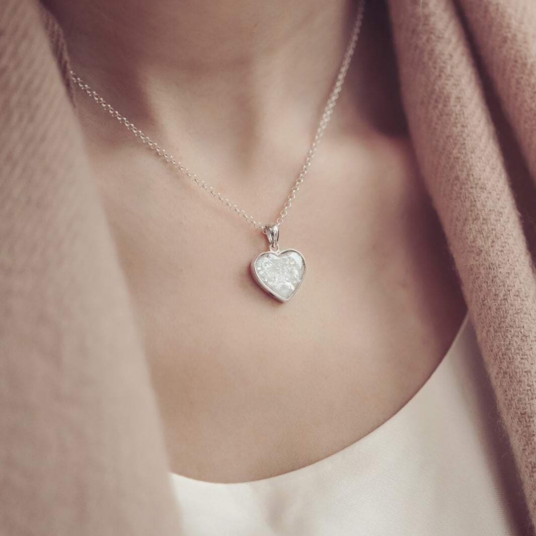 Lady wearing a Sterling silver heart necklace with a central section filled with memorial ashes and white crushed crystals